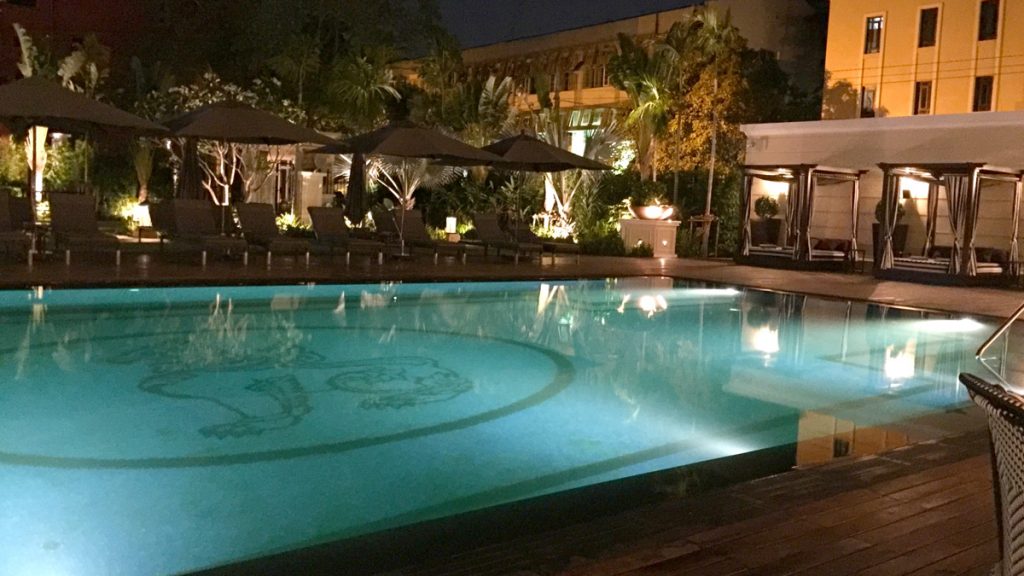 a pool with umbrellas and chairs in front of a building