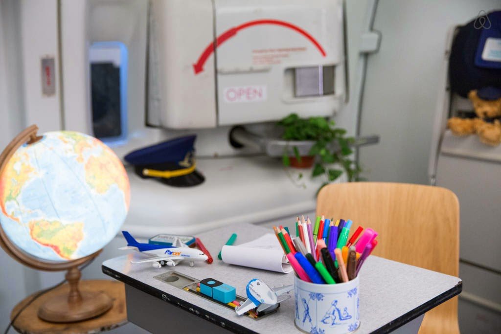 a desk with a globe and a plane and pens on it