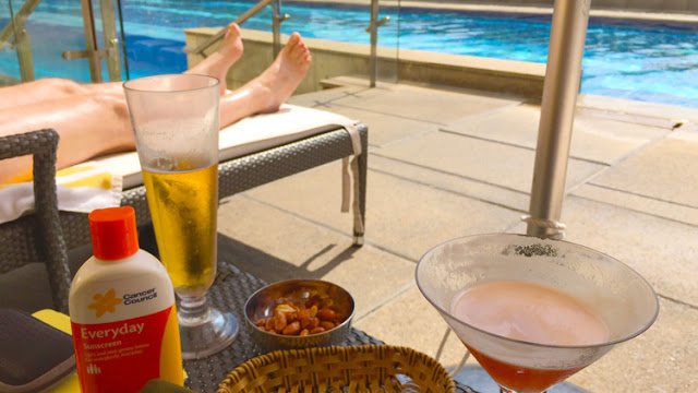 a table with drinks and snacks on it by a pool