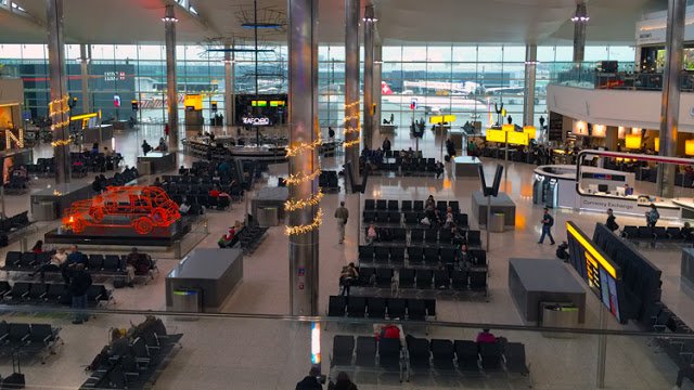 a large airport terminal with many people sitting in chairs