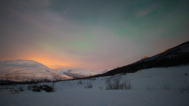 a snowy landscape with mountains and stars