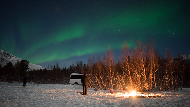 a person standing in front of a campfire in the snow