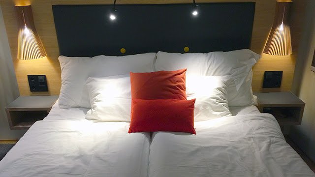a bed with pillows and a red pillow on it