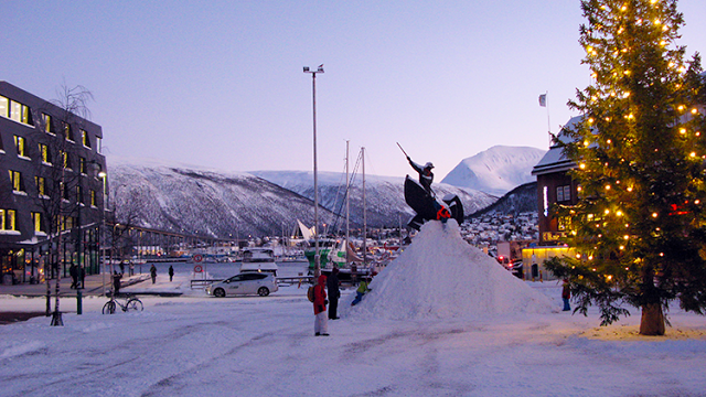 a statue of a man on a motorcycle on a pile of snow