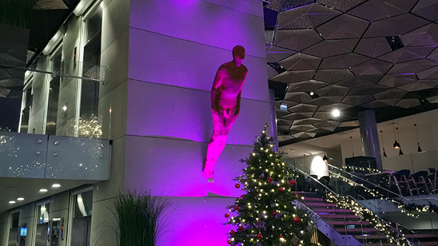 a tree with lights and a statue on the wall