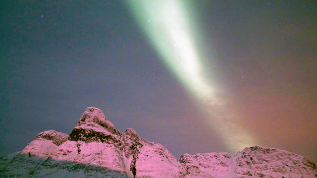 a aurora borealis in the sky over snowy mountains