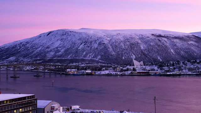 a body of water with snow covered mountains and a city