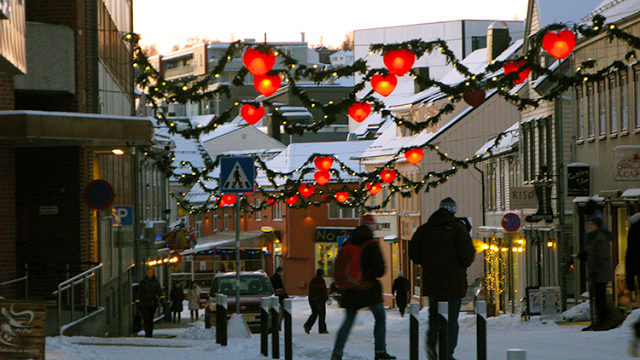 people walking on a snowy street with lights and people walking