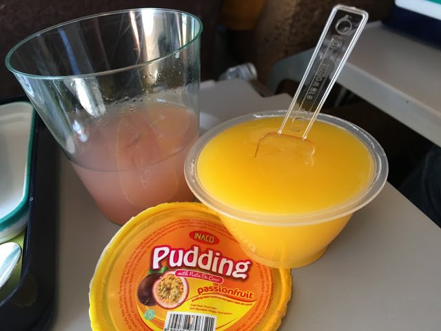 a plastic cup with a spoon in it next to a cup of orange liquid