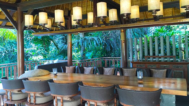 a table with chairs and lamps in a room with trees in the background