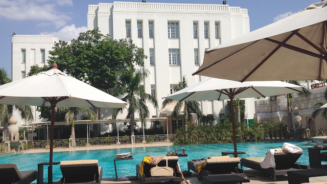 a pool with umbrellas and chairs in front of a building