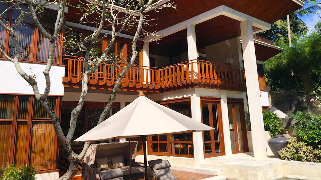 a patio with a white umbrella and a couch in front of a building