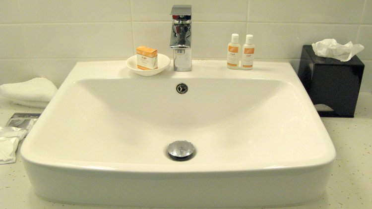 a bathroom sink with a soap dish and bottles of shampoo