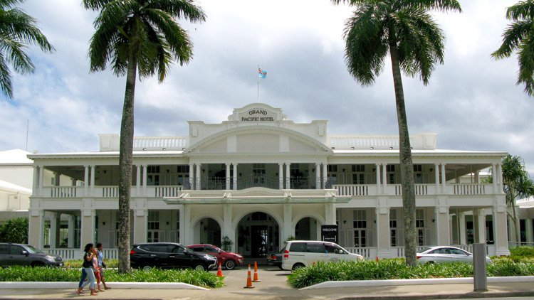 a white building with palm trees and cars