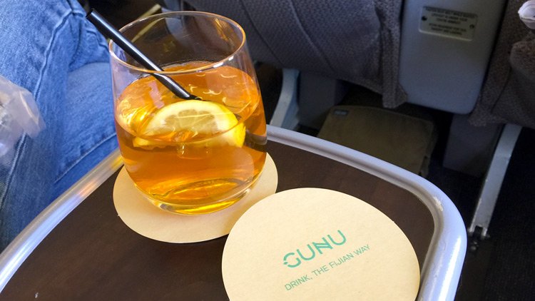 a glass of liquid with a lemon slice and a straw on a tray