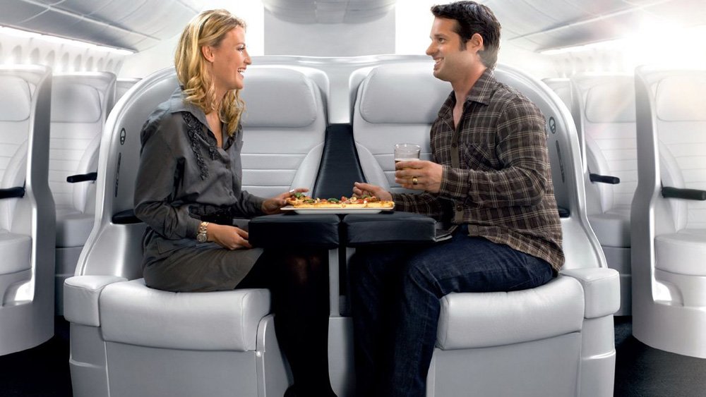 a man and woman sitting in a chair with food on the table