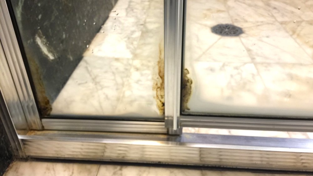 a dirty glass door with a drain