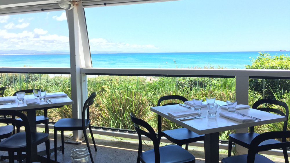 a table and chairs outside with a view of the ocean