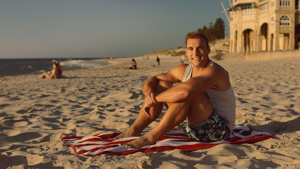 a man sitting on a towel on a beach