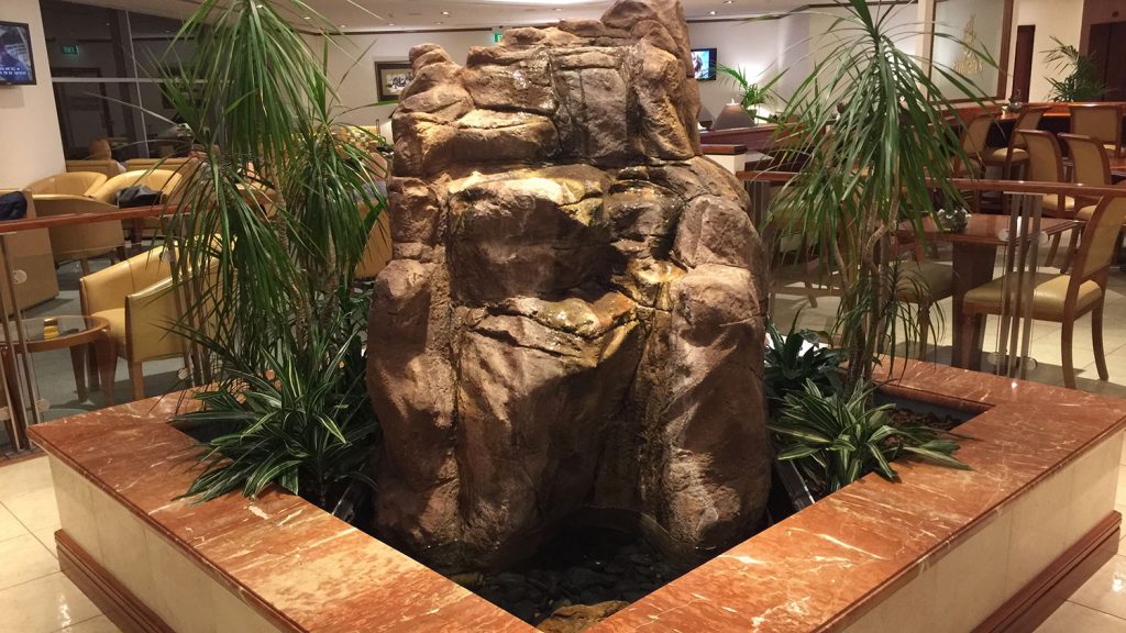 a rock fountain with plants around it