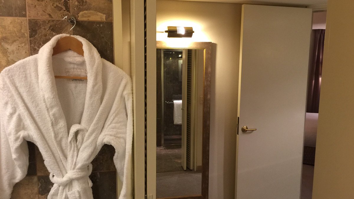 a white bathrobe on a swinger next to a mirror