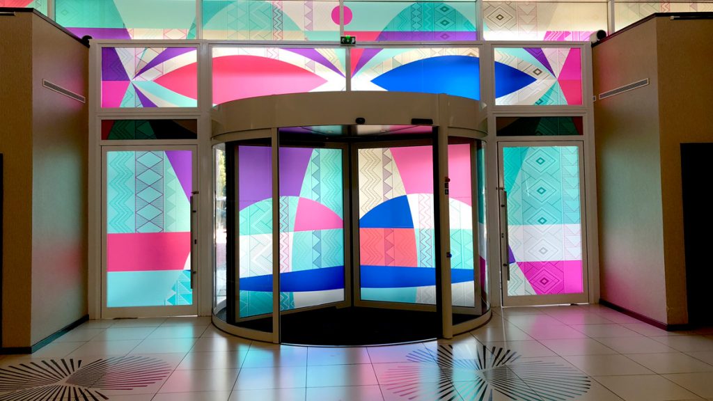 a glass door with colorful designs on the wall