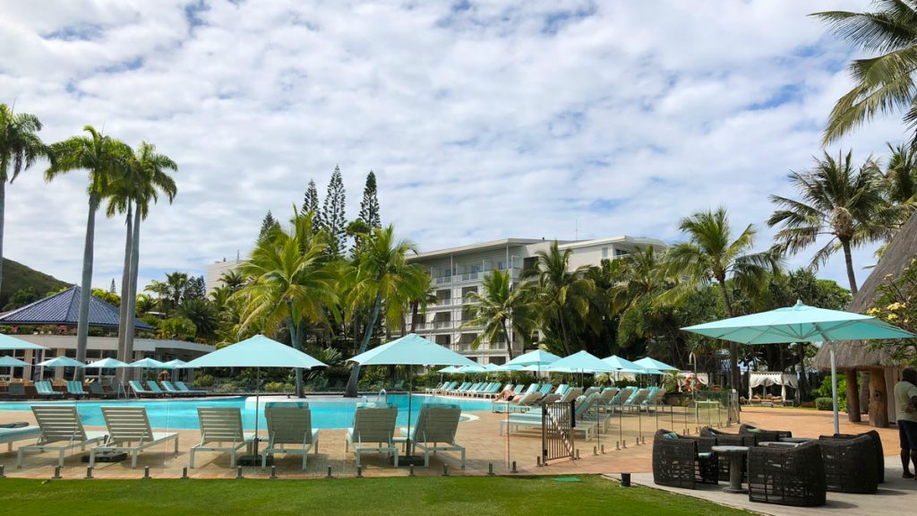 a pool with umbrellas and chairs in front of a building