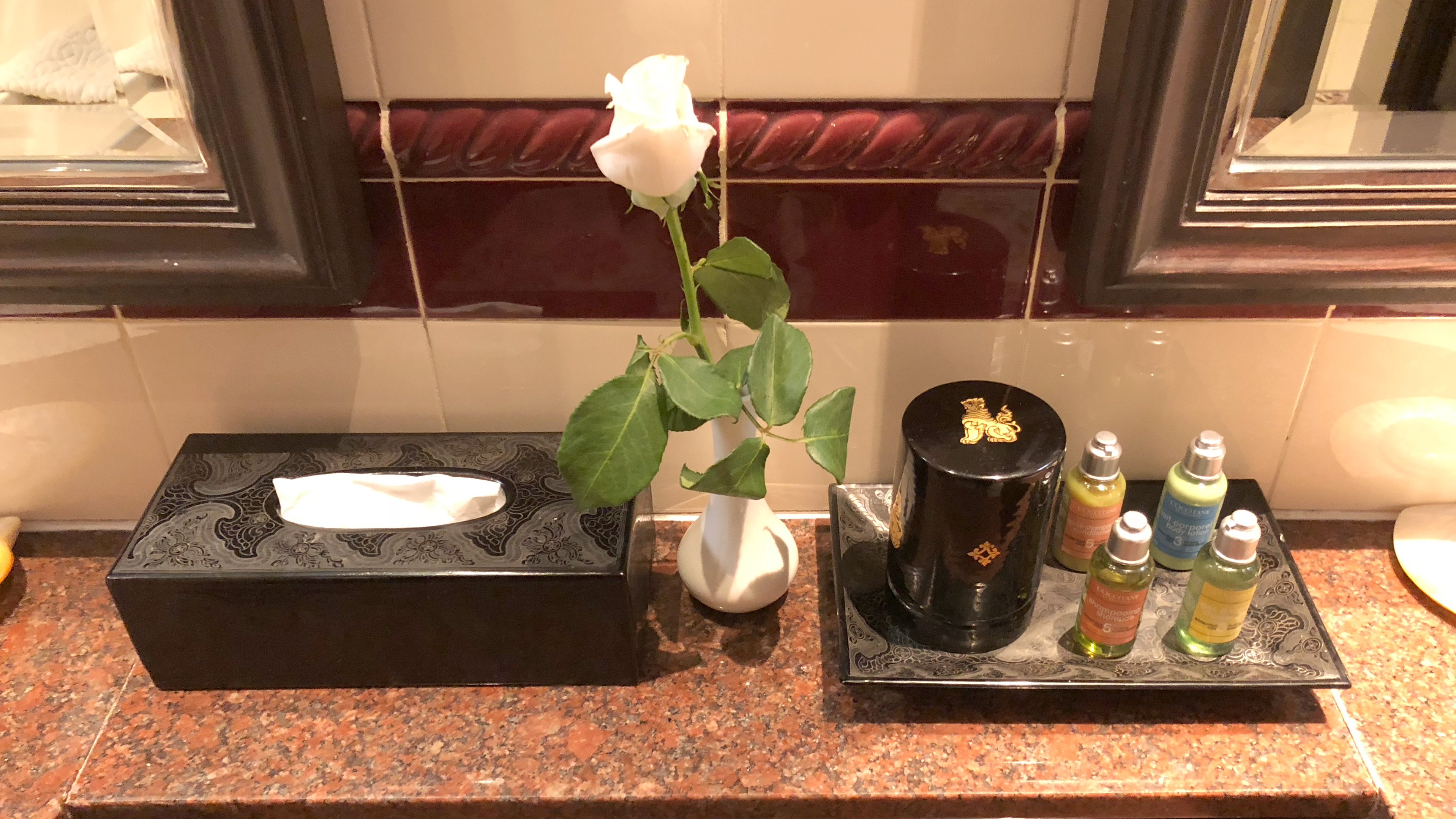 a white rose in a white vase on a counter