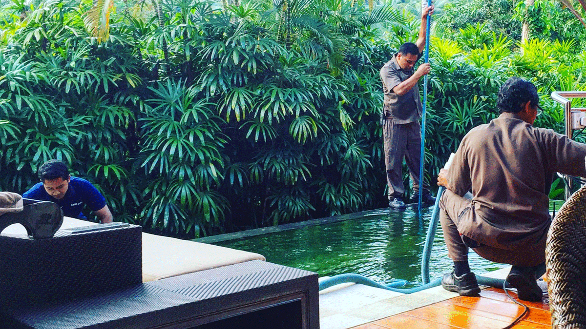 a man holding a hose to a woman in a pool