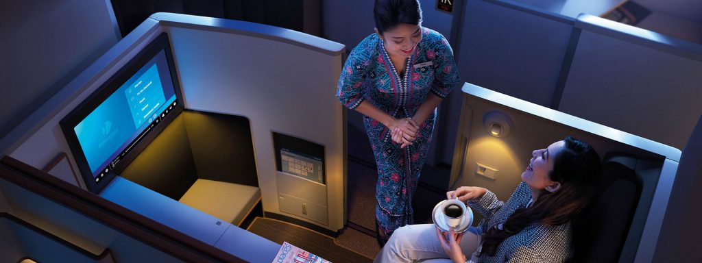a woman holding a cup of coffee and a man sitting in an airplane