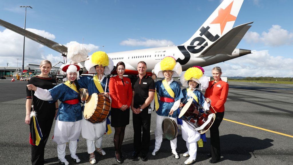 a group of people in clothing standing in front of an airplane