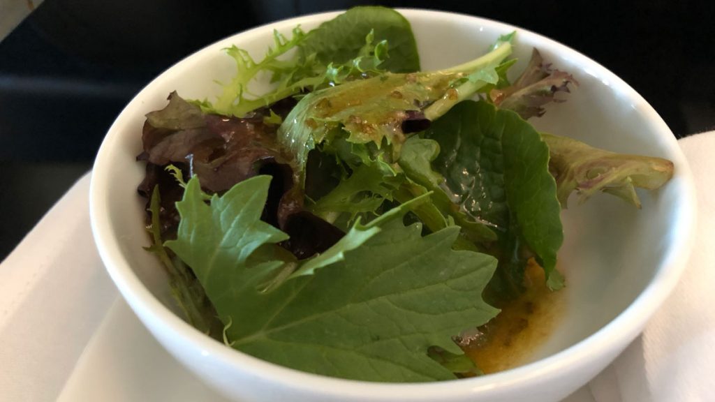 a bowl of salad with lettuce and mustard