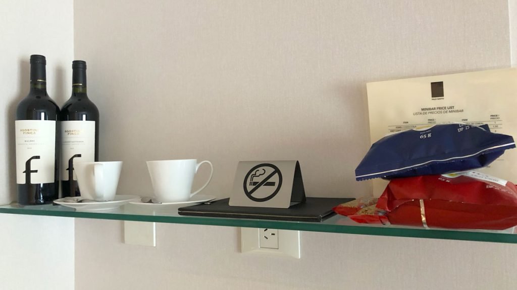a glass shelf with a sign and cups on it