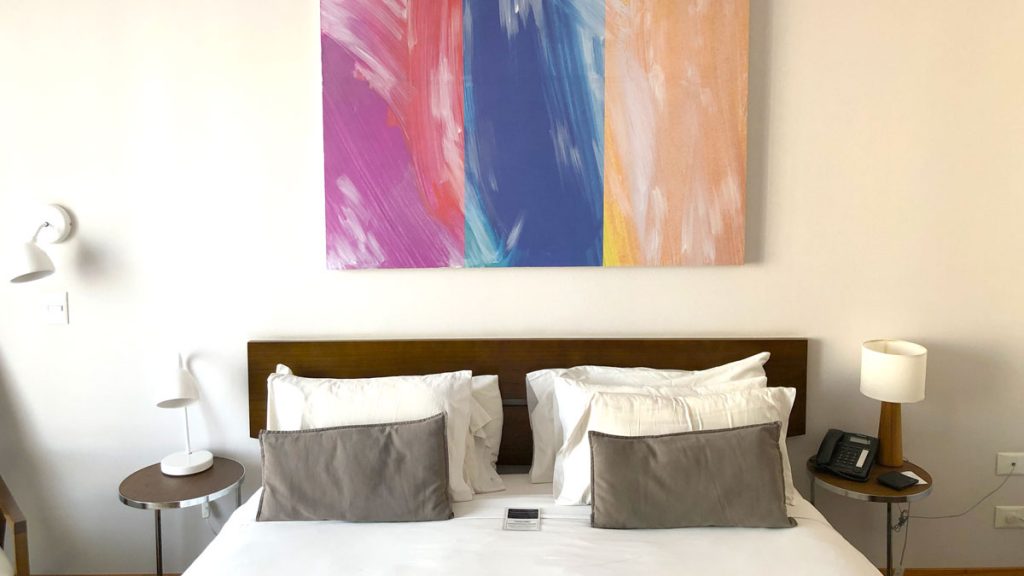 a bed with pillows and a painting on the wall