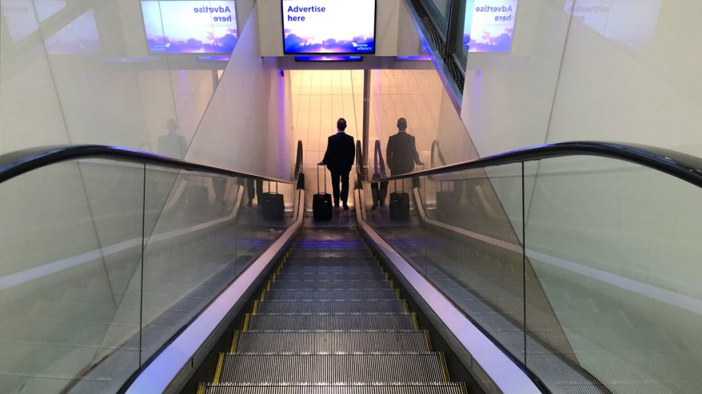 a man with luggage walking down an escalator