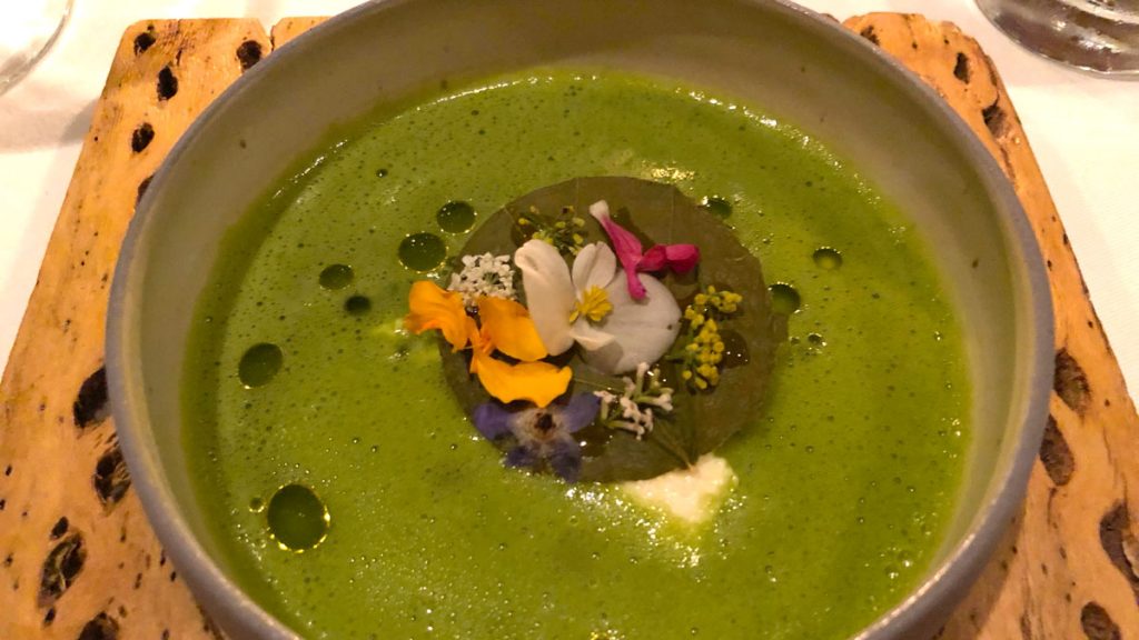 a bowl of green soup with flowers