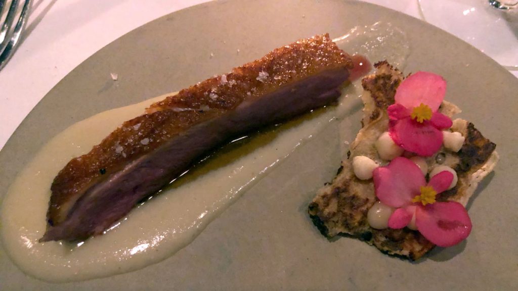 a piece of meat with sauce and rose petals on a plate