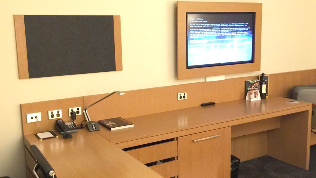 a desk with a computer and a television on the wall