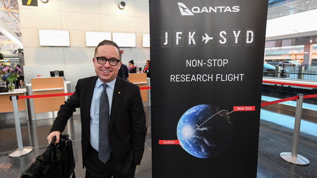 a man in a suit and tie standing next to a sign