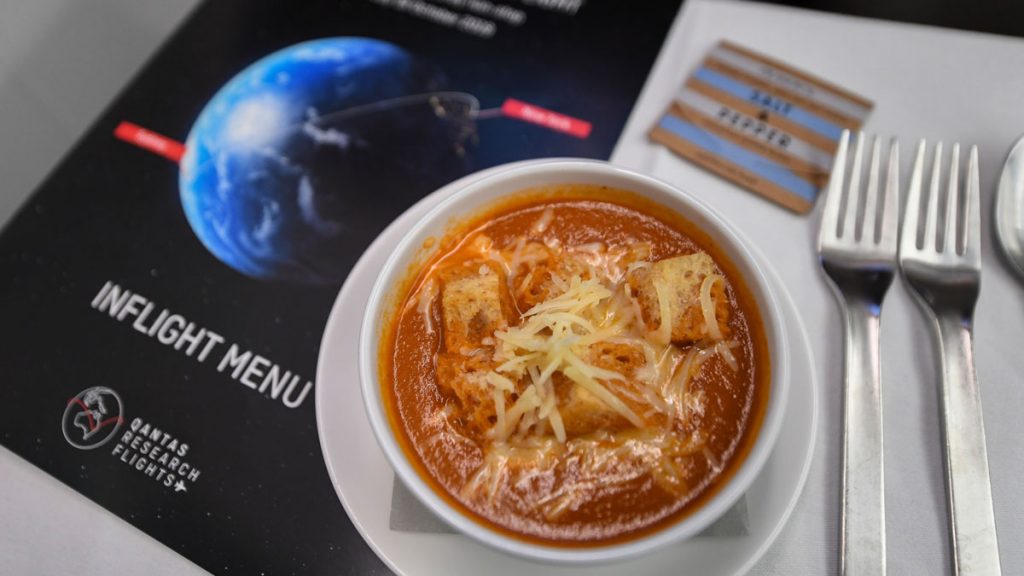 a bowl of soup with cheese and croutons