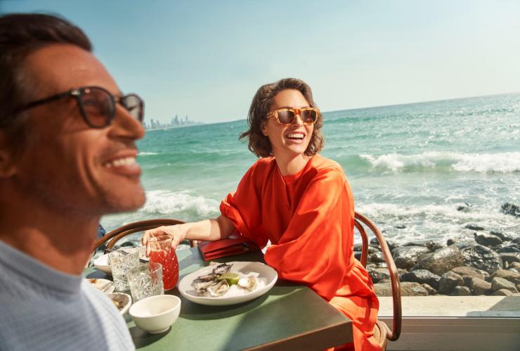 a man and woman sitting at a table with food on it