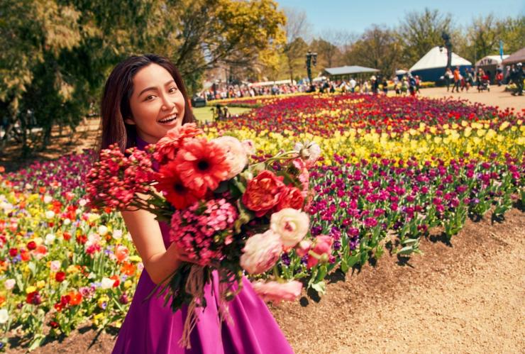 a woman holding flowers in a garden