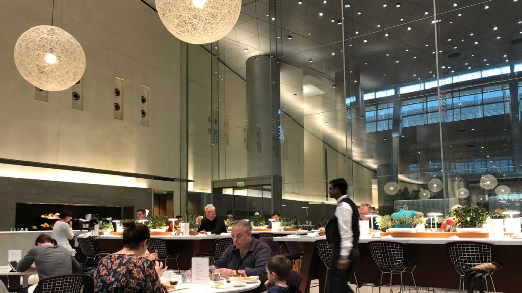 a group of people sitting at tables in a room with glass walls