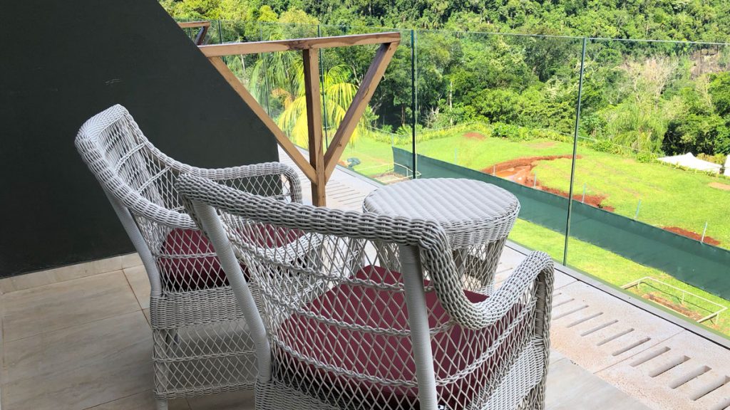 a white wicker chairs on a deck overlooking a green field