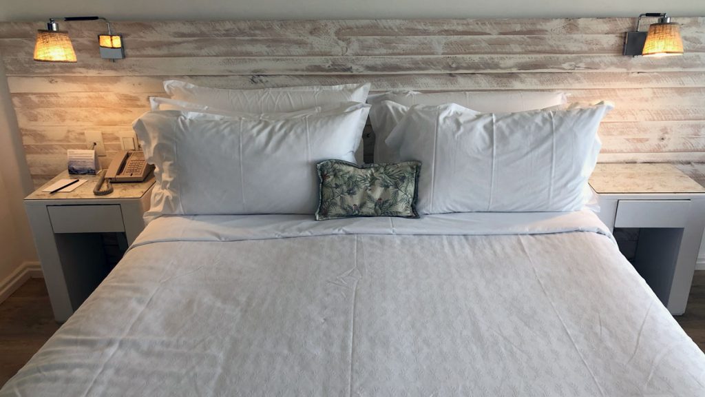 a bed with white sheets and pillows