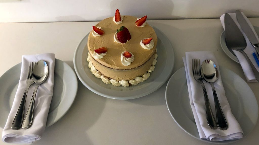 a cake with strawberries on top and a plate with plates and silverware