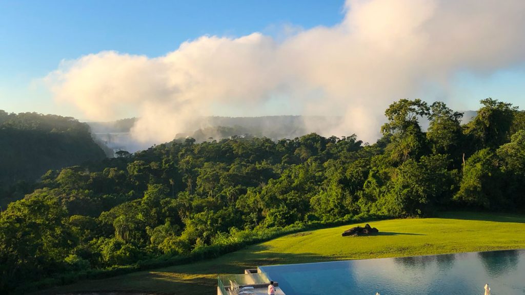 a pool with a view of a forest and a blue sky