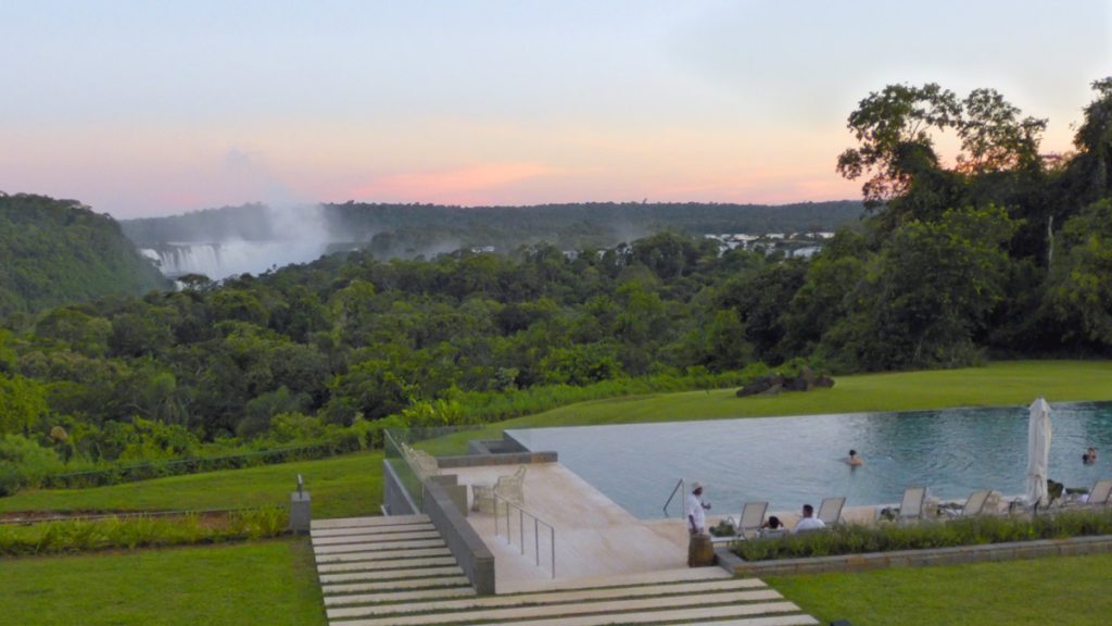 a pool with a pool in the middle of a grassy area with trees and a cloudy sky