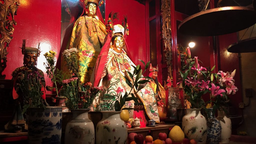 a group of statues in a room with vases and fruit