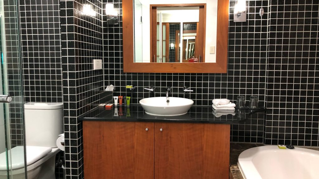 a bathroom with a black tile wall and a white sink